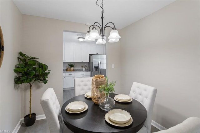 dining area featuring an inviting chandelier, baseboards, and dark wood finished floors
