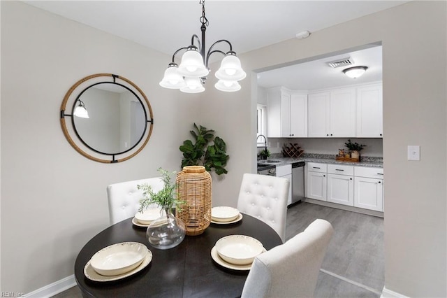 dining space featuring an inviting chandelier, baseboards, and wood finished floors
