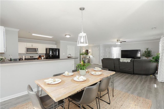 dining space featuring crown molding, a ceiling fan, light wood-style flooring, and baseboards