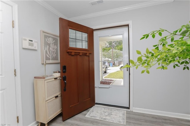 entryway with baseboards, ornamental molding, light wood-style flooring, and visible vents