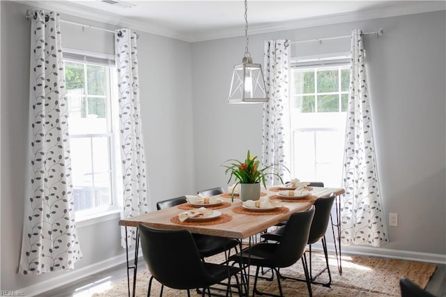 dining area with crown molding, baseboards, a healthy amount of sunlight, and wood finished floors