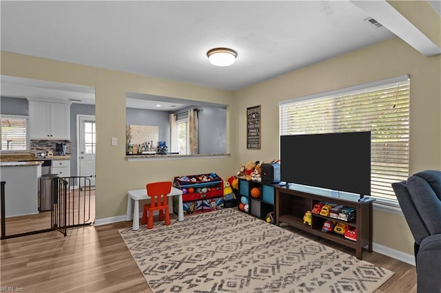 game room with baseboards, wood finished floors, and visible vents