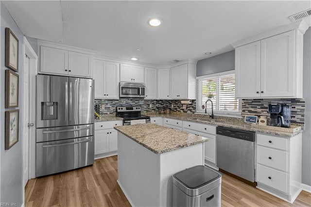 kitchen with a sink, stainless steel appliances, white cabinetry, and visible vents