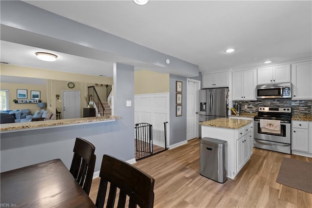 kitchen with light wood-style floors, white cabinetry, backsplash, and stainless steel appliances