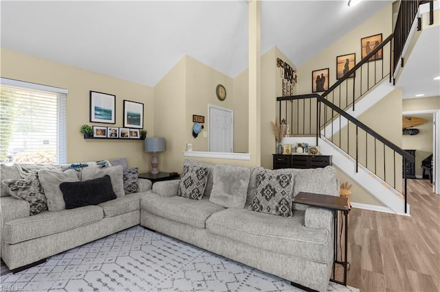 living area featuring high vaulted ceiling, baseboards, stairs, and wood finished floors