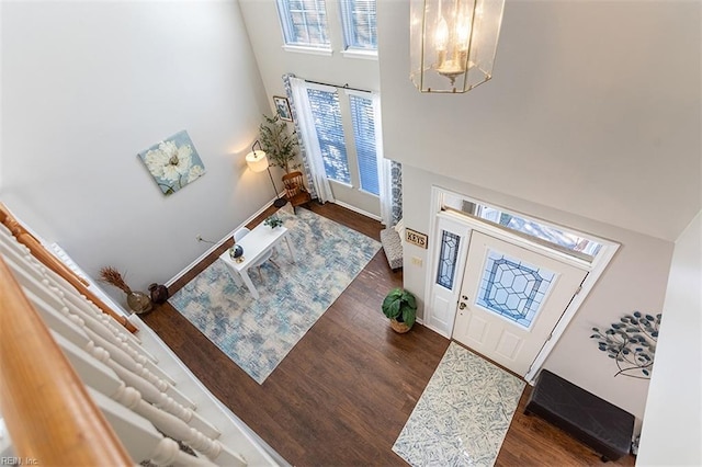entryway with plenty of natural light, a high ceiling, an inviting chandelier, and wood finished floors