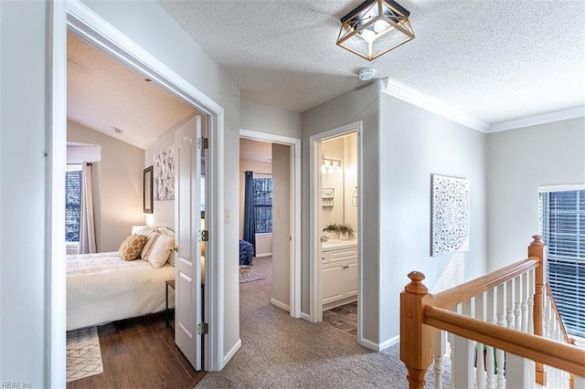 corridor featuring crown molding, baseboards, a textured ceiling, and an upstairs landing