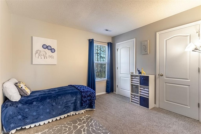 carpeted bedroom with visible vents, a textured ceiling, and baseboards