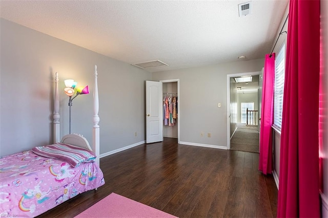 bedroom with baseboards, attic access, wood finished floors, and a spacious closet