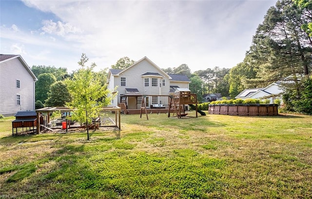 back of house with a playground, a yard, and an outdoor pool