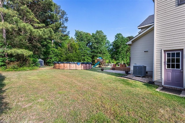 view of yard featuring a playground, central AC, and an outdoor pool