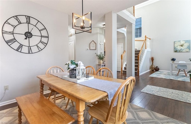 dining room featuring stairway, baseboards, wood finished floors, and a notable chandelier