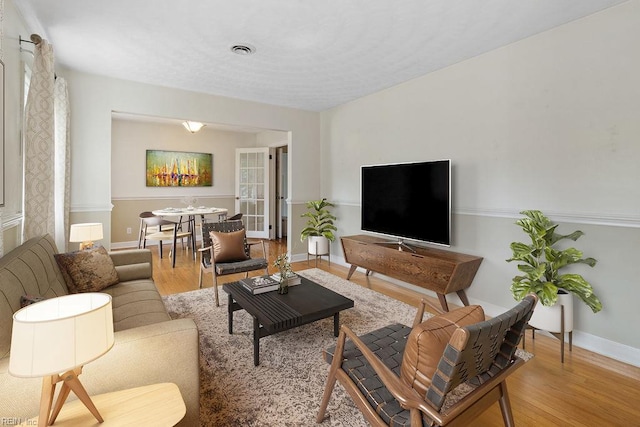 living room with baseboards, wood finished floors, and visible vents