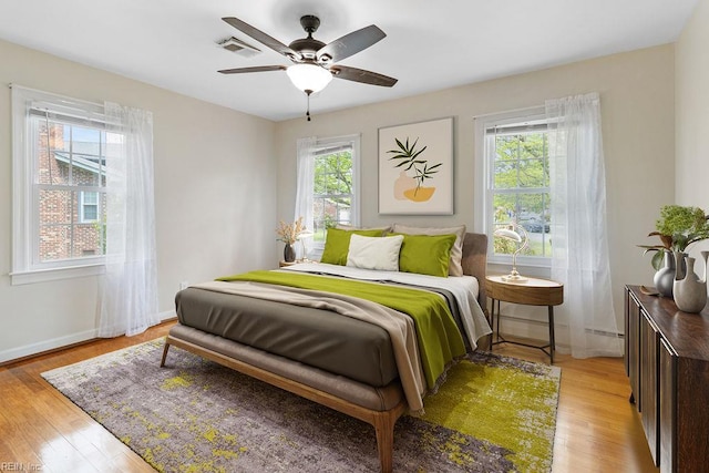bedroom with visible vents, light wood-style flooring, ceiling fan, and baseboards