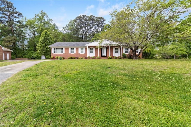 ranch-style house with driveway, a front lawn, and brick siding