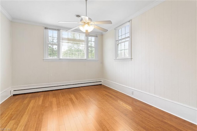 spare room featuring plenty of natural light, baseboard heating, a ceiling fan, and wood finished floors