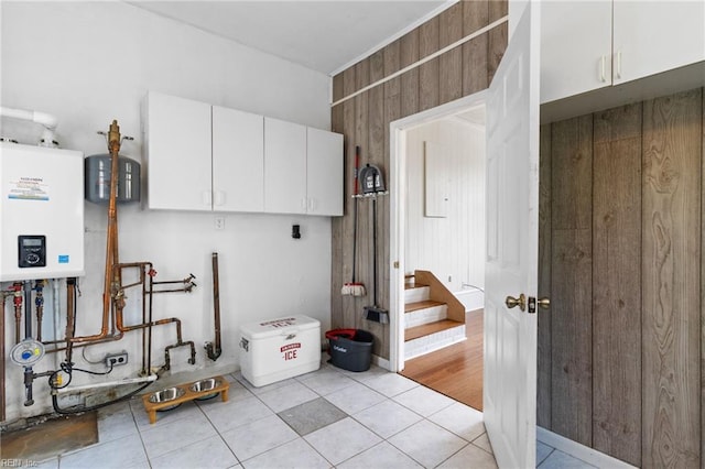 laundry room with wooden walls, tankless water heater, and light tile patterned floors