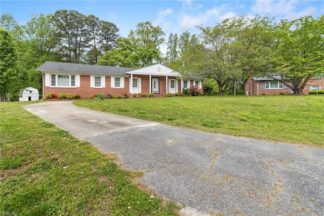 view of front of house with brick siding, driveway, and a front yard