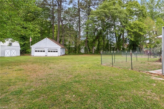 view of yard featuring a detached garage, fence, and an outbuilding