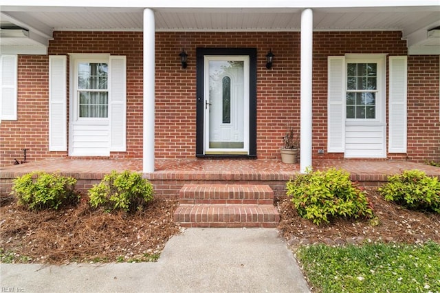 property entrance featuring covered porch and brick siding