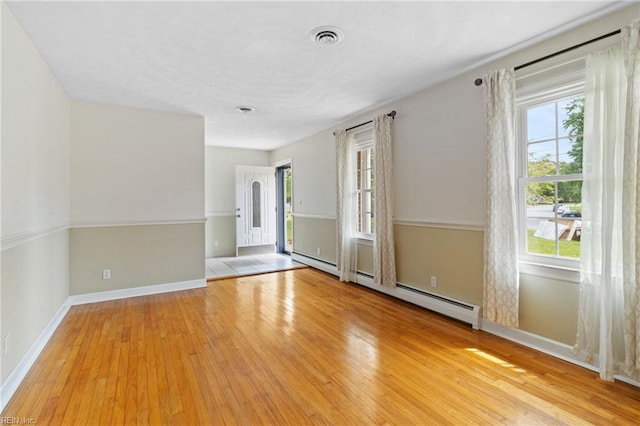 unfurnished room with plenty of natural light, hardwood / wood-style flooring, and visible vents