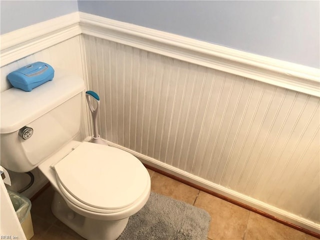bathroom featuring tile patterned flooring, wainscoting, and toilet