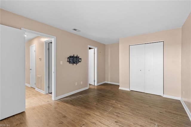 unfurnished bedroom with wood finished floors, baseboards, and a closet
