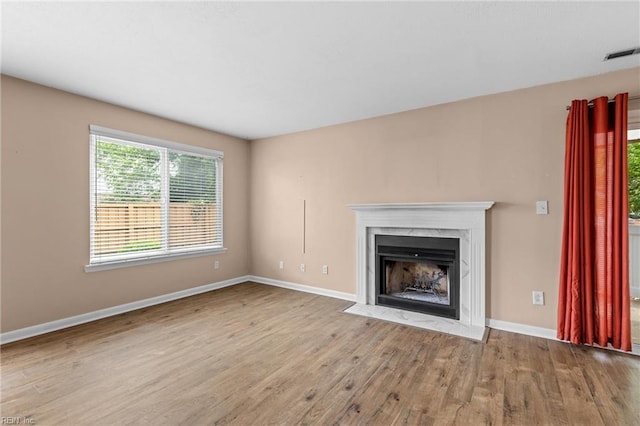 unfurnished living room featuring wood finished floors, plenty of natural light, baseboards, and a fireplace