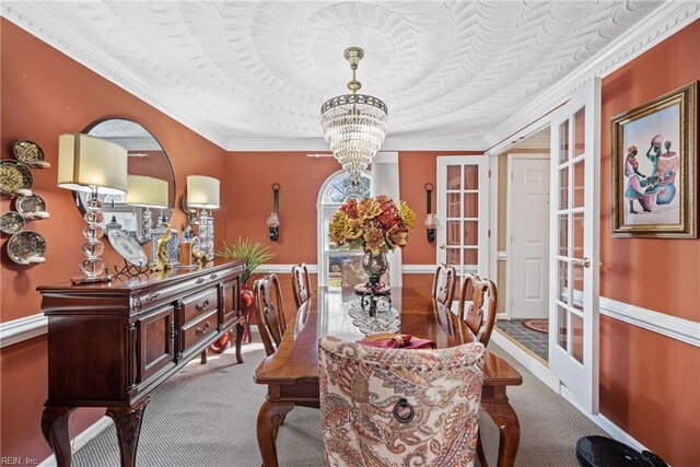 carpeted dining room with ornamental molding, french doors, and a chandelier