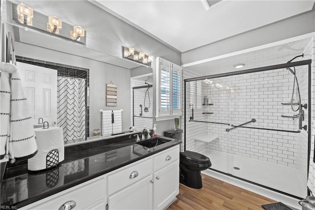 bathroom featuring vanity, toilet, a shower stall, wood finished floors, and visible vents