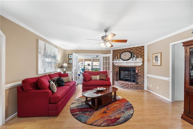 living area with crown molding, a ceiling fan, light wood-style flooring, and a brick fireplace