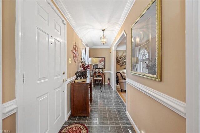 hallway with baseboards, ornamental molding, and a chandelier