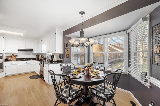 dining room with a notable chandelier, light wood finished floors, baseboards, visible vents, and ornamental molding