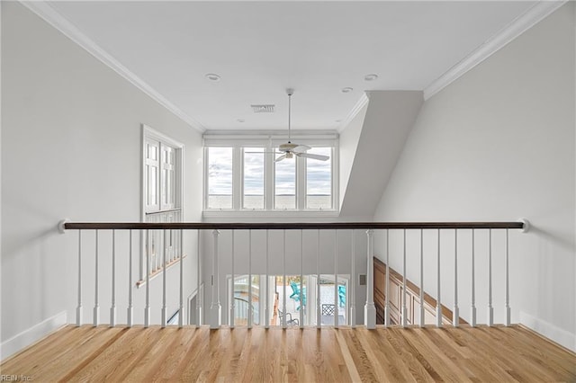 interior space featuring visible vents, ornamental molding, wood finished floors, baseboards, and a ceiling fan