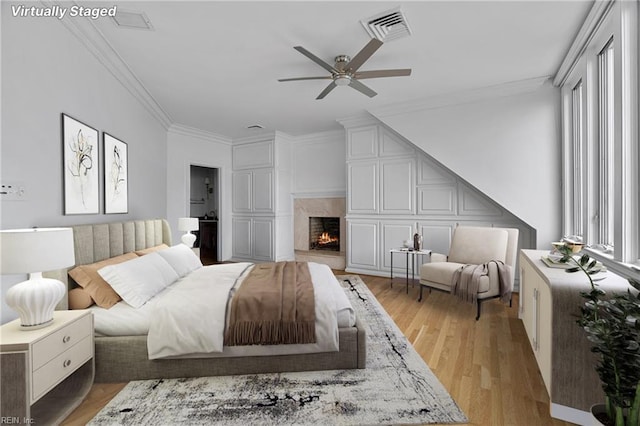 bedroom with visible vents, ornamental molding, a high end fireplace, and light wood-type flooring