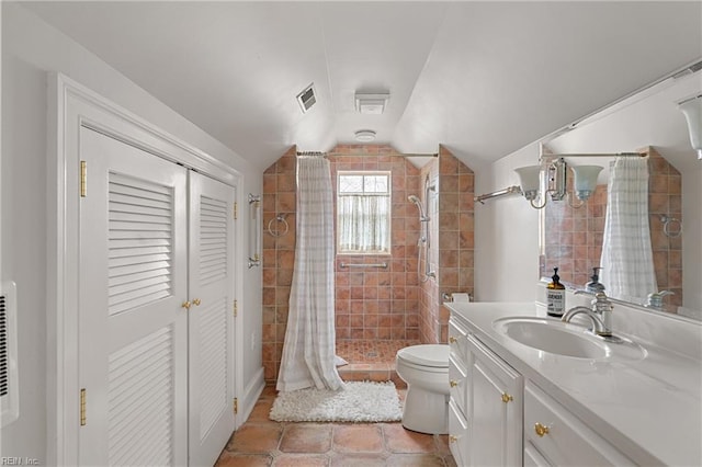 bathroom featuring tile patterned flooring, vanity, lofted ceiling, toilet, and a stall shower
