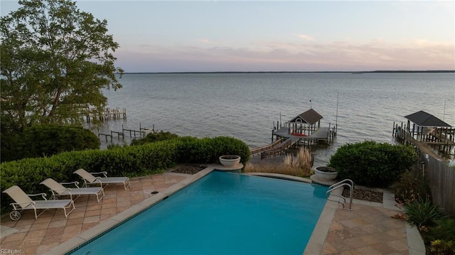 outdoor pool featuring a boat dock, boat lift, a water view, and a patio