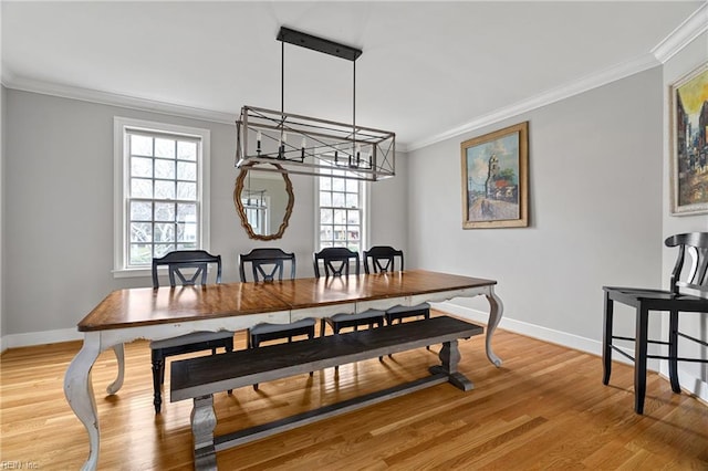 dining space with baseboards, ornamental molding, an inviting chandelier, and light wood-type flooring