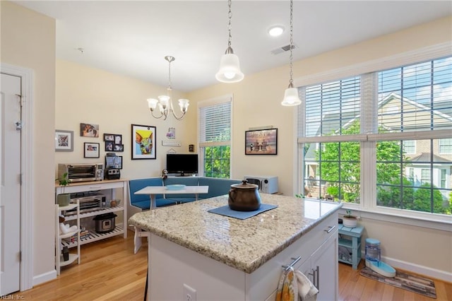 kitchen with an inviting chandelier, baseboards, light wood-type flooring, a kitchen island, and visible vents