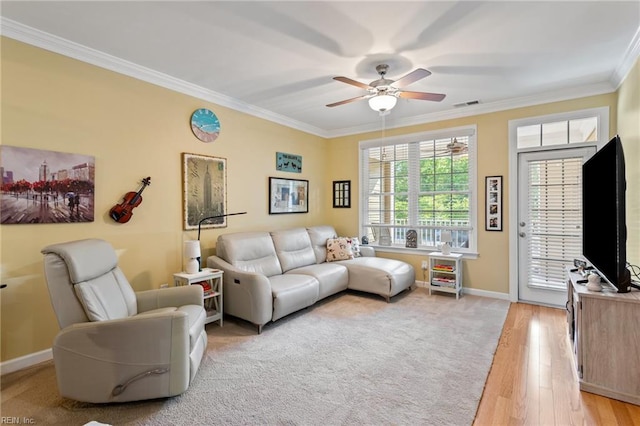 living area featuring baseboards, ornamental molding, a ceiling fan, and visible vents