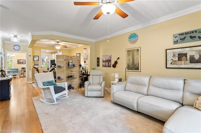 living room with baseboards, ornamental molding, a ceiling fan, and light wood-type flooring
