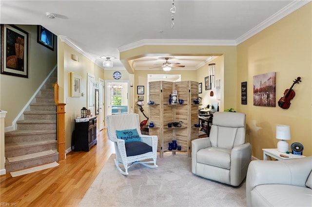 living room featuring crown molding, light wood-style floors, stairs, a ceiling fan, and baseboards
