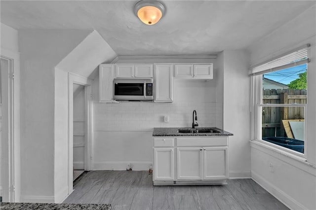 37 Farragut St, Portsmouth, VA 23702 - kitchen with a sink, dark stone counters, white cabinetry, stainless steel microwave, and decorative backsplash