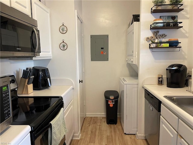 kitchen with stainless steel appliances, white cabinetry, light wood-type flooring, stacked washer and clothes dryer, and electric panel