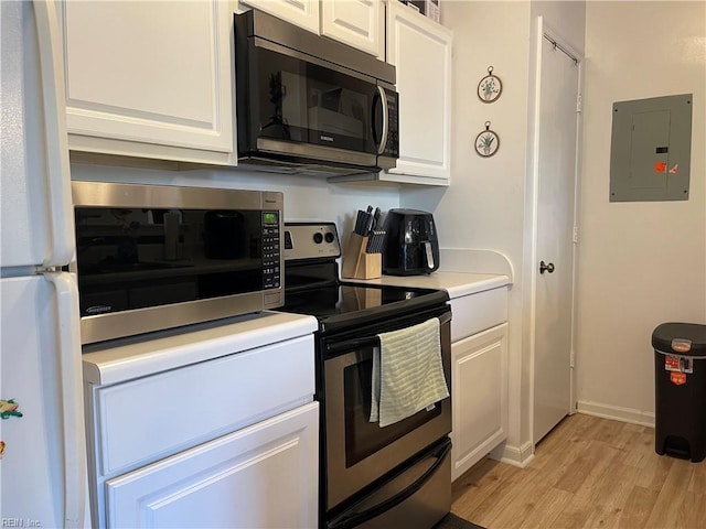 kitchen with electric panel, appliances with stainless steel finishes, light countertops, light wood-style floors, and white cabinetry