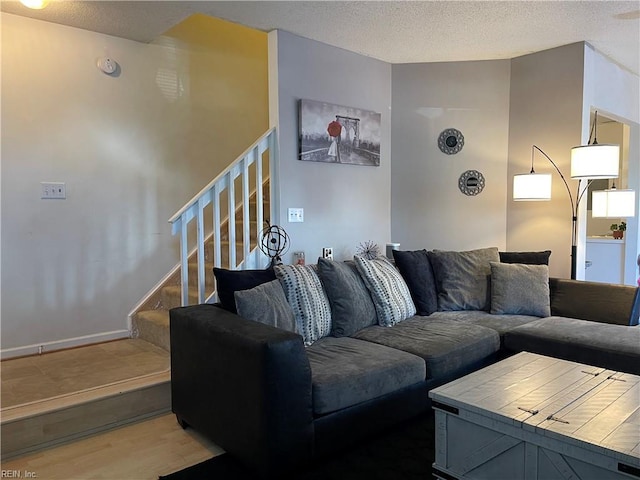 living room with stairs, a textured ceiling, and wood finished floors