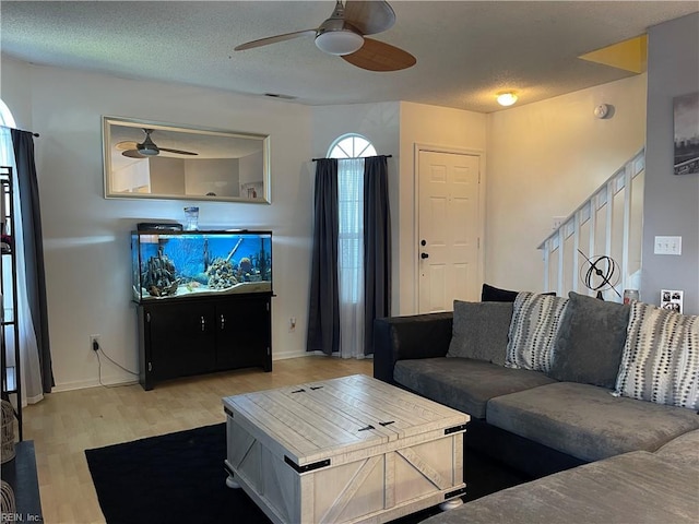 living room featuring stairs, a ceiling fan, baseboards, wood finished floors, and visible vents