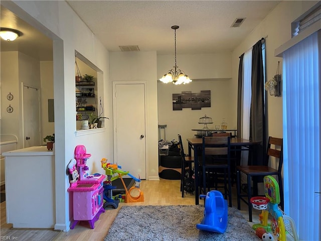 dining area featuring visible vents, wood finished floors, and a notable chandelier