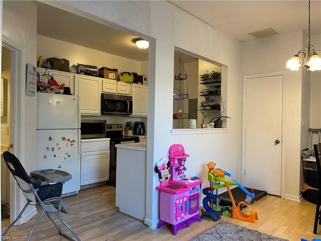 kitchen with light wood-style floors, appliances with stainless steel finishes, an inviting chandelier, and visible vents