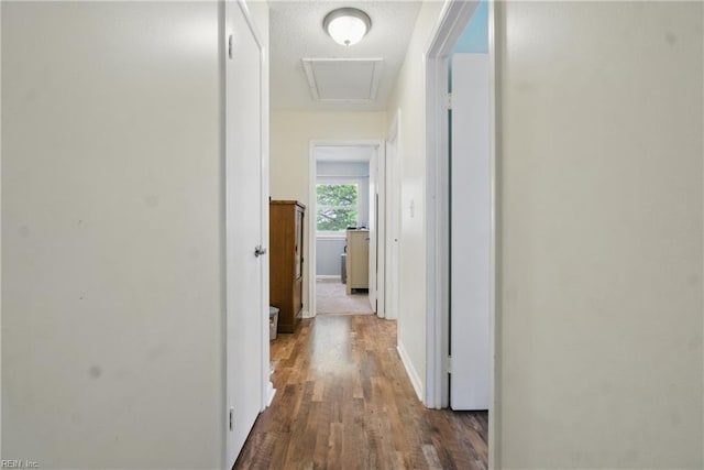 corridor featuring baseboards, attic access, and wood finished floors